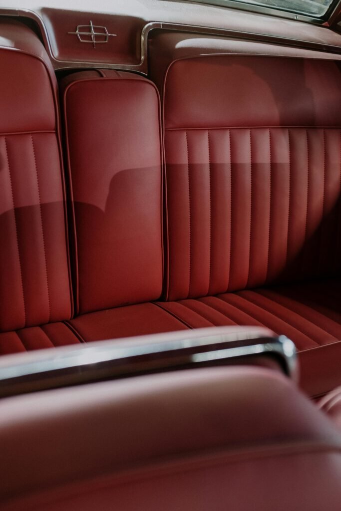 Classic car interior showcasing elegant red leather seating and retro design details.